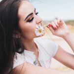 woman in white shirt holding white flower during daytime