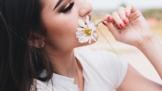 woman in white shirt holding white flower during daytime