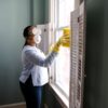 woman in white long sleeve shirt and blue denim jeans standing beside white wooden framed glass