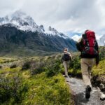 two person walking towards mountain covered with snow