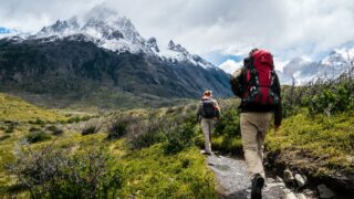 two person walking towards mountain covered with snow