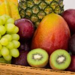 red apple fruit beside green apple and yellow fruit on brown woven basket