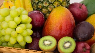 red apple fruit beside green apple and yellow fruit on brown woven basket