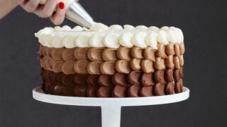 person holding white ice cream cone with brown and white round cake