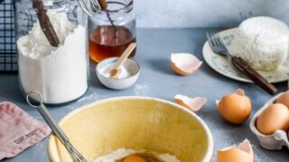 brown mixing bowl with eggs and flour with whisk