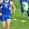 man in blue Champion tank top and shorts running at the field