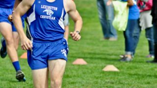 man in blue Champion tank top and shorts running at the field